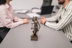 Lady Justice statue on table between two people during divorce consultation