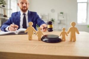 judge holding gavel beside wooden family figurines on desk during legal proceeding