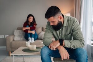 man and woman sitting apart on couch during domestic dispute at home